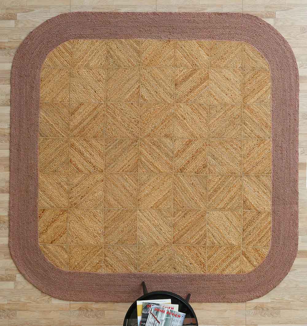 The RAMSHA HOME Natural & Rust Color Braided Outdoor Rug - BR 094 rests on a light wood floor. A small round black table with magazines sits at the bottom center edge of the rug.