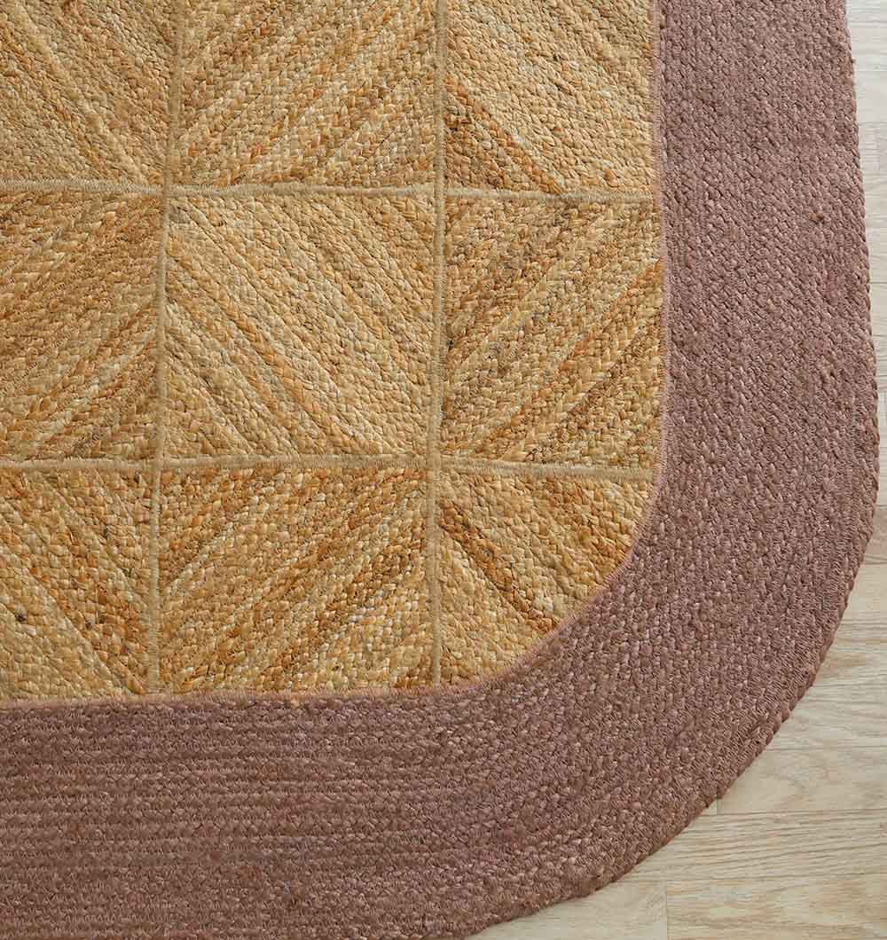 Close-up of the RAMSHA HOME Natural & Rust Color Braided Outdoor Rug (BR 094), showcasing a chevron pattern and thick solid rust border, laid on a light wooden floor.