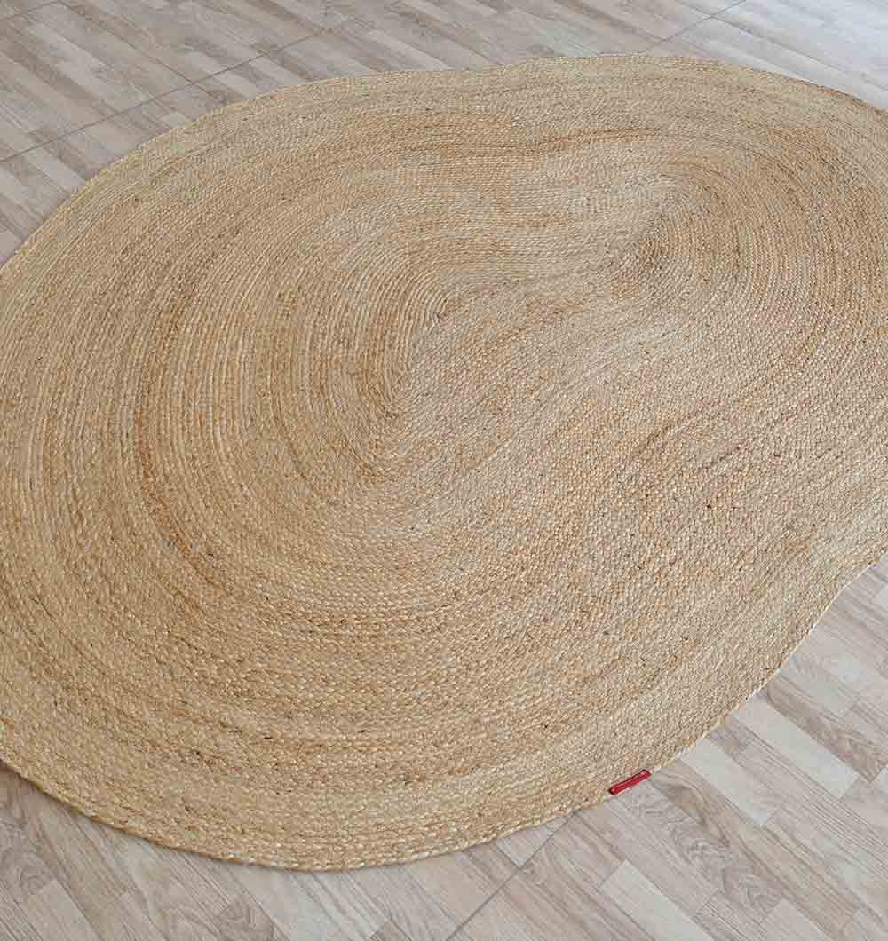 The RAMSHA HOME Natural Color Shaped Braided Outdoor Rug 170X240 CM (BR 097) features a natural tan hue, bringing organic decor to the space as it lies on a light wood floor.