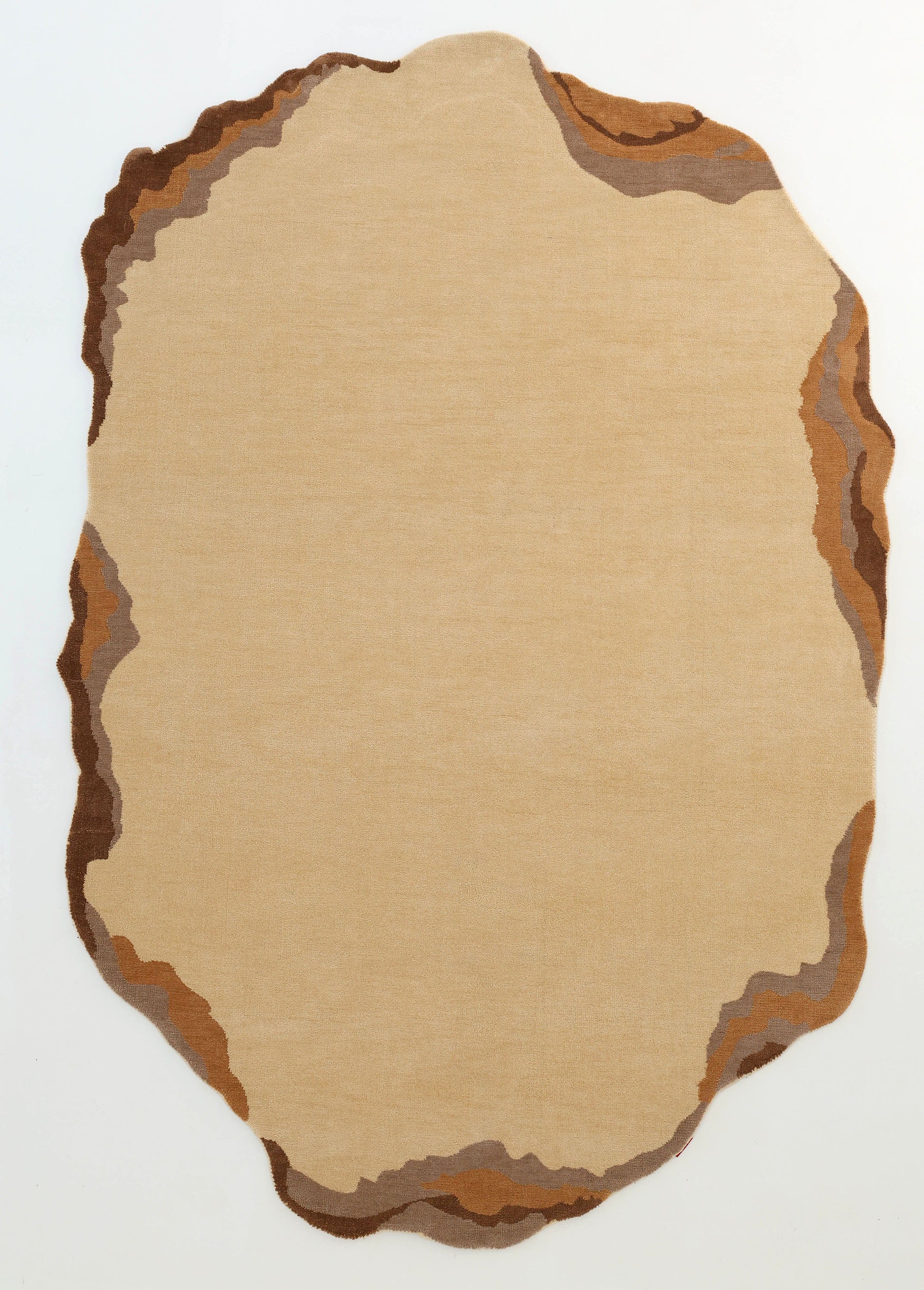 The Earth Layers Contemporary Rug Shaped Rug CMN 119 by RAMSHA HOME features an irregular beige design with wavy brown, tan, and gray borders plus an abstract stone-like pattern on a white background.