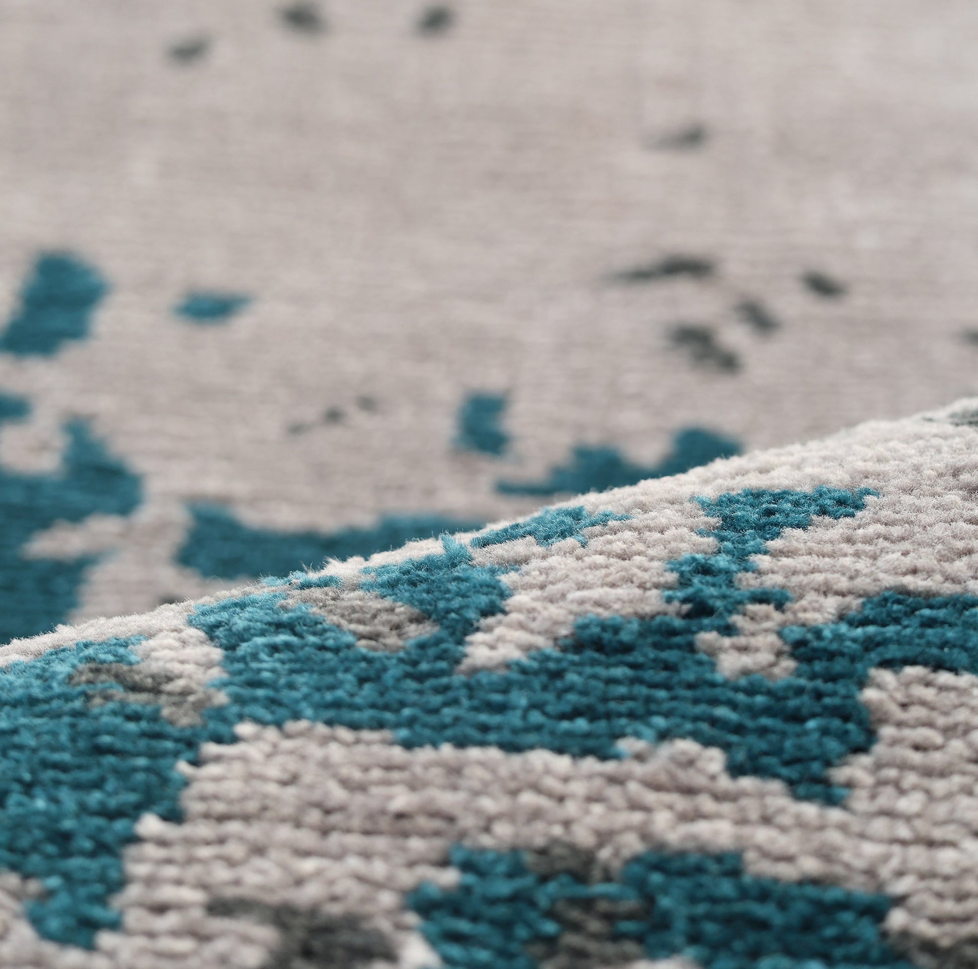 Close-up of RAMSHA HOME's Modern Blue Round Abstract Rug CMN 121, showing raised geometric patterns in teal and gray. The detailed shot highlights the intricate fibers and surface variations.