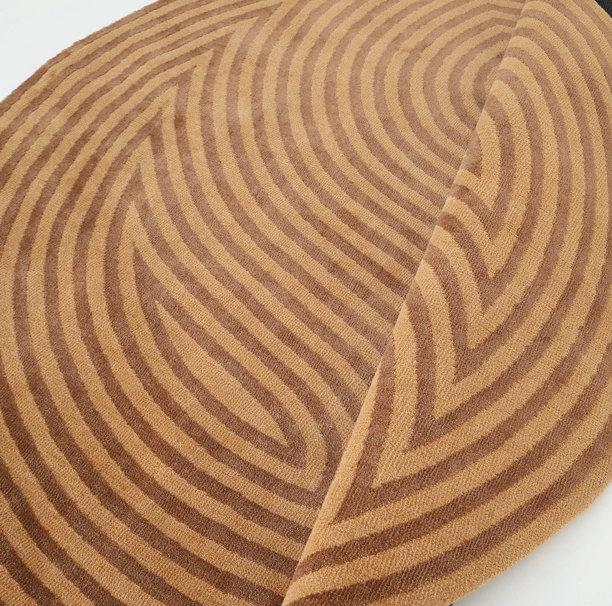 The RAMSHA HOME Modern Brown Color Round Abstract Rug CMN 130 features raised wavy geometric patterns in brown tones, with one edge folded to show texture and thickness—ideal for a contemporary space.
