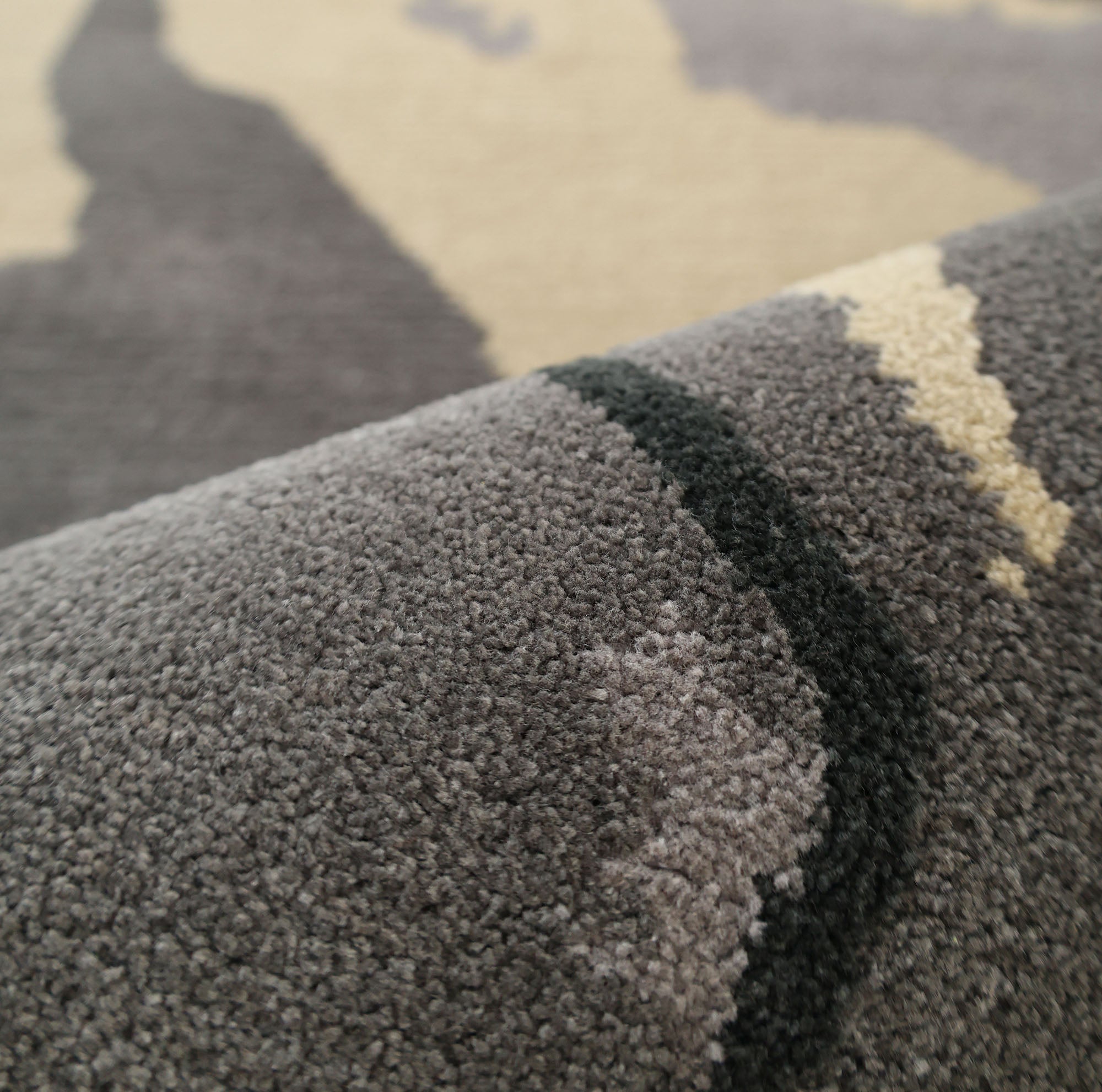 Close-up of the RAMSHA HOME Modern Geometric Round Rug CMN 133, featuring textured fibers and a pattern in grey and beige. The image showcases the rug’s contemporary design and surface detail.