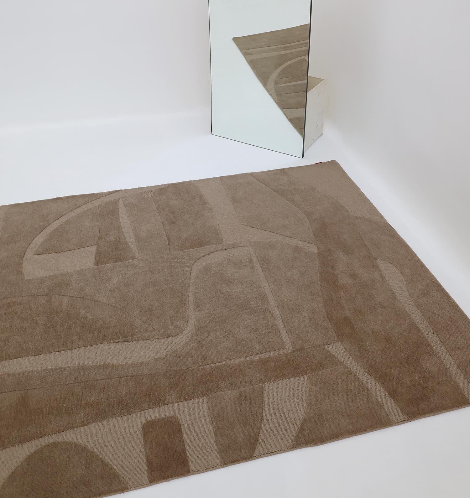 A RAMSHA HOME Dark Tone Multi Color Polyester CMN-19 rug sits on a white floor beside a rectangular mirror that reflects the vibrant area rug and minimalist white walls.