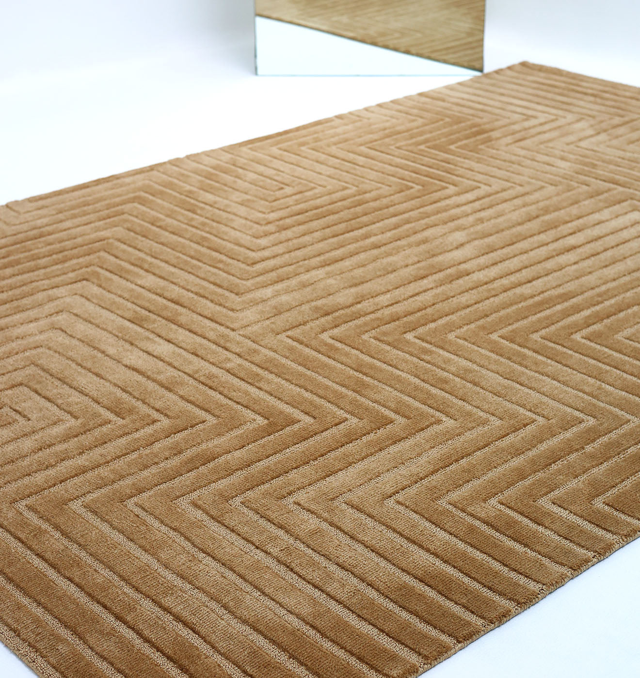 The Novara Rugs Multi Color Polyester CMN-20 by RAMSHA HOME, featuring a geometric zigzag design in beige, is placed on a white floor with its edge reflected in a nearby mirror.