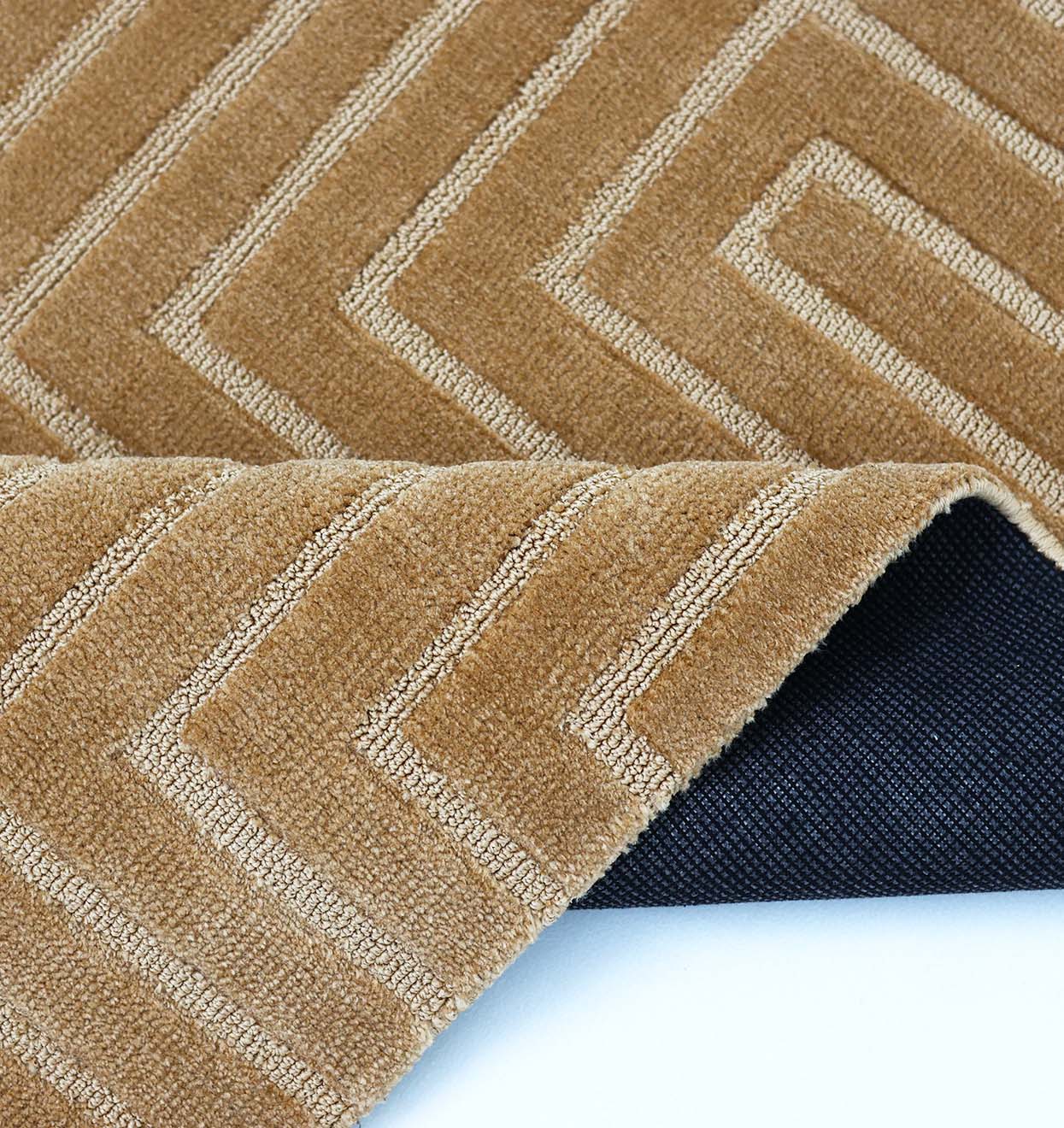 A close-up of the RAMSHA HOME Novara Rugs Multi Color Polyester CMN-20 highlights its geometric zigzag pattern and textured top, with one corner folded to reveal the dark non-slip backing.