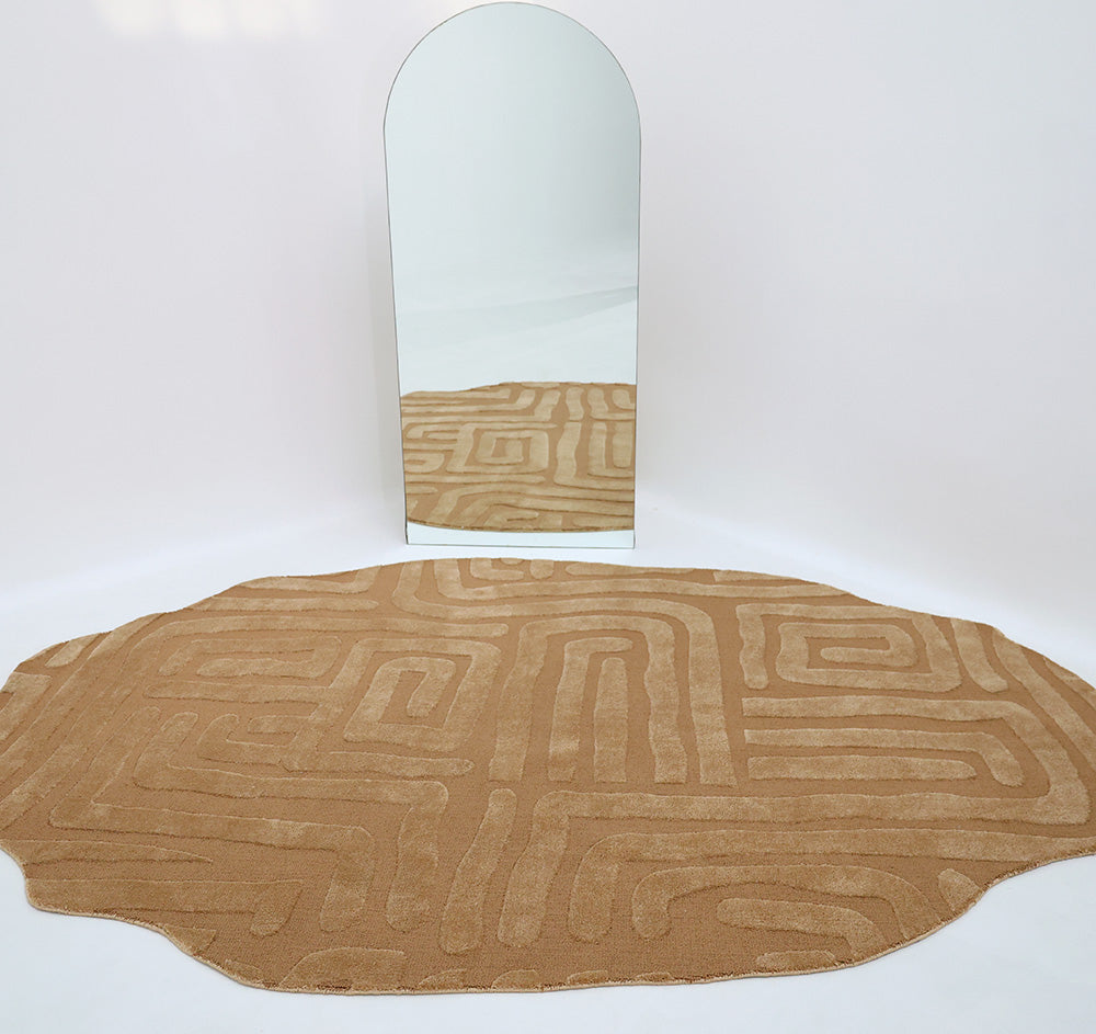 The Amazing Brown Color Unshape Decor Rug- CMN 26 (200x300cm) by RAMSHA HOME, featuring a modern maze-like pattern and irregular shape, is placed in front of a tall arched mirror on a plain white background.