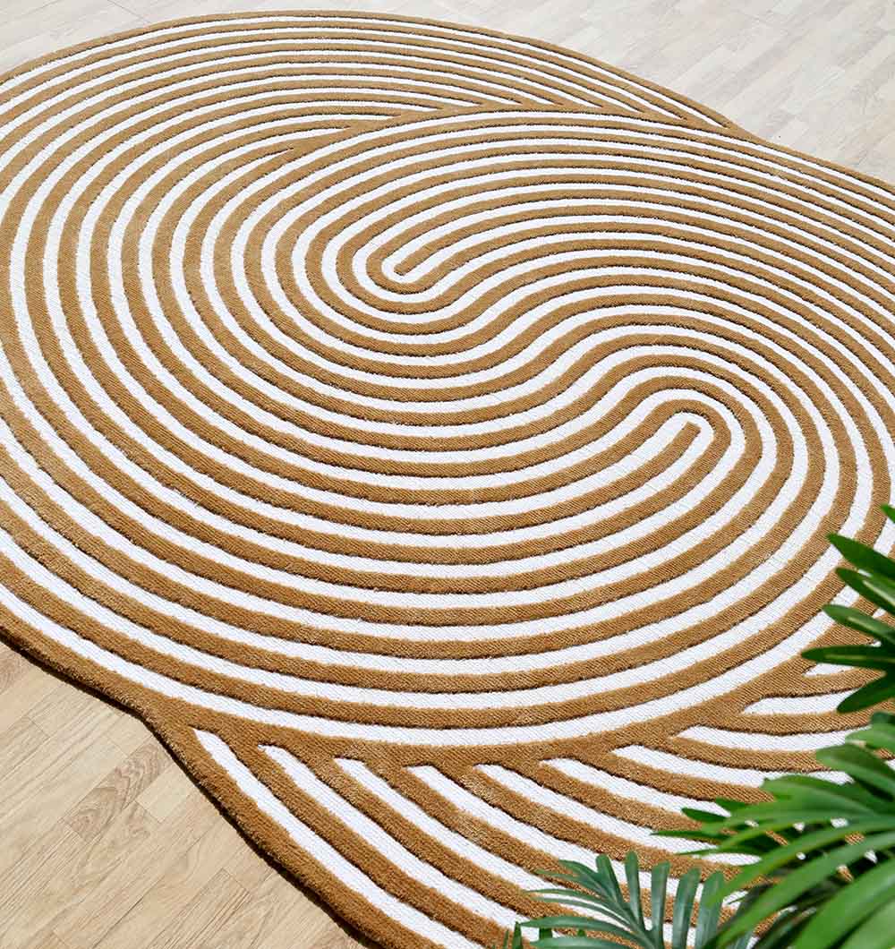 The RAMSHA HOME Novara Rug Ramsha Indian Multi Color - CMN 29 (195x280cm) features a modern tan and white concentric pattern, making a statement on a light wooden floor with green plant leaves in view.