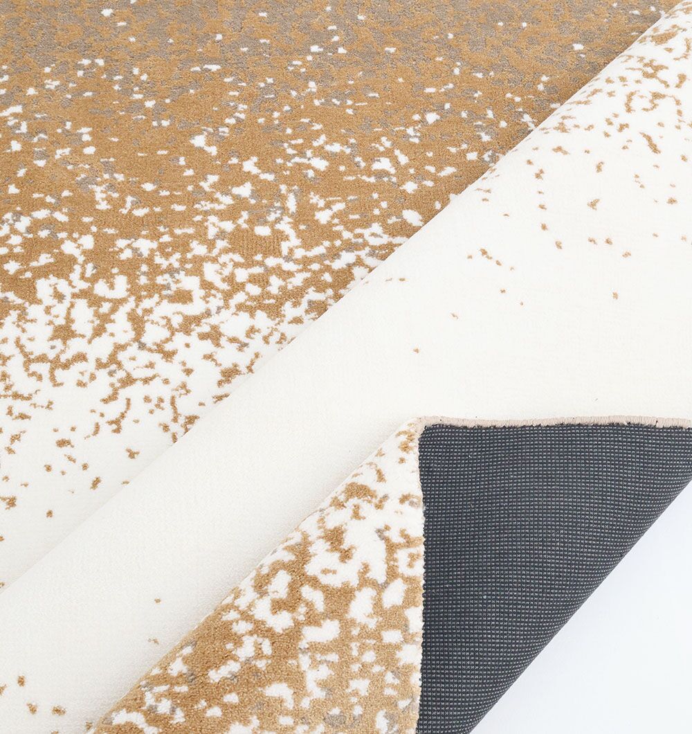 A close-up of the RAMSHA HOME Rectangle Multi Color Rug - CMN 70 (200x300cm), featuring a white base with gold speckles, partially folded to reveal its dark gray textured backing.