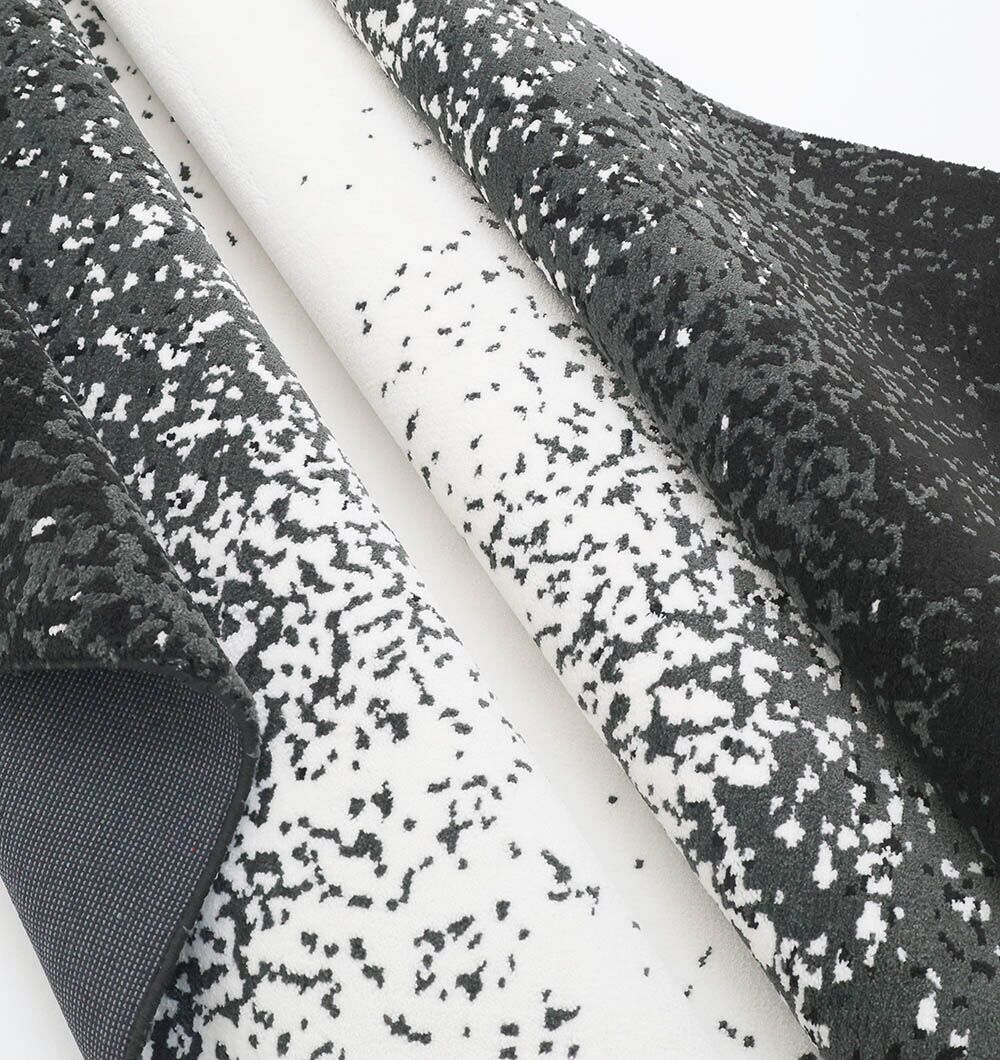 The Rectangle Multi Color Rug - CMN 71 (200x300cm) from RAMSHA HOME features a machine-made, abstract pixelated black and white design with contrasting light and dark sides, highlighting its unique textured speckled pattern.
