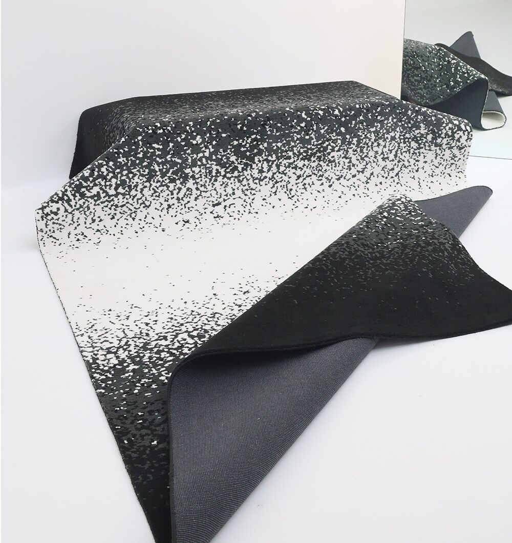 The RAMSHA HOME Rectangle Multi Color Rug - CMN 71 (200x300cm) is partially rolled and placed before a mirror, which reflects its unique gradient speckled pattern and stylish edges.
