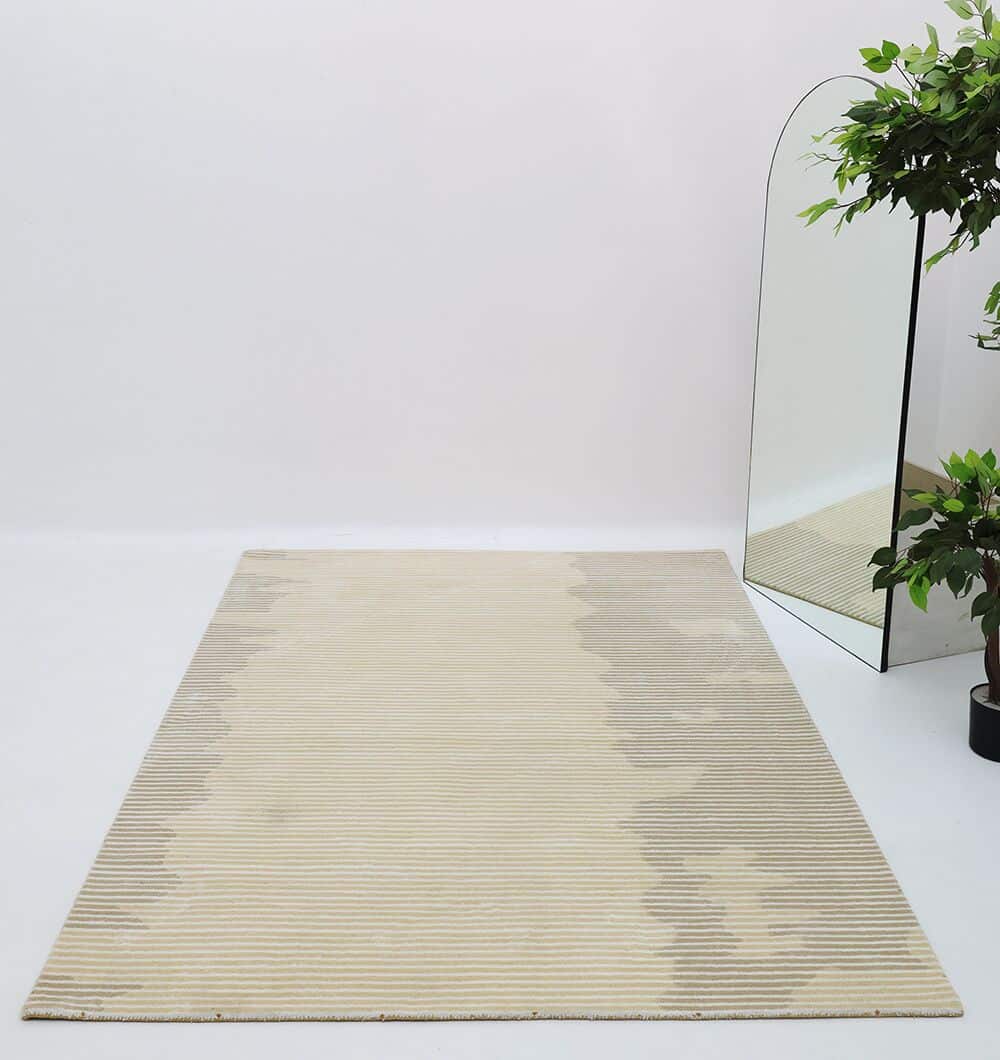 The RAMSHA HOME Novara Rug - CMN 81 with beige and gray stripes lies on a light floor. A large arched mirror and a leafy green plant in a black pot sit in the corner, reflecting the rug and adding to the minimalist decor.