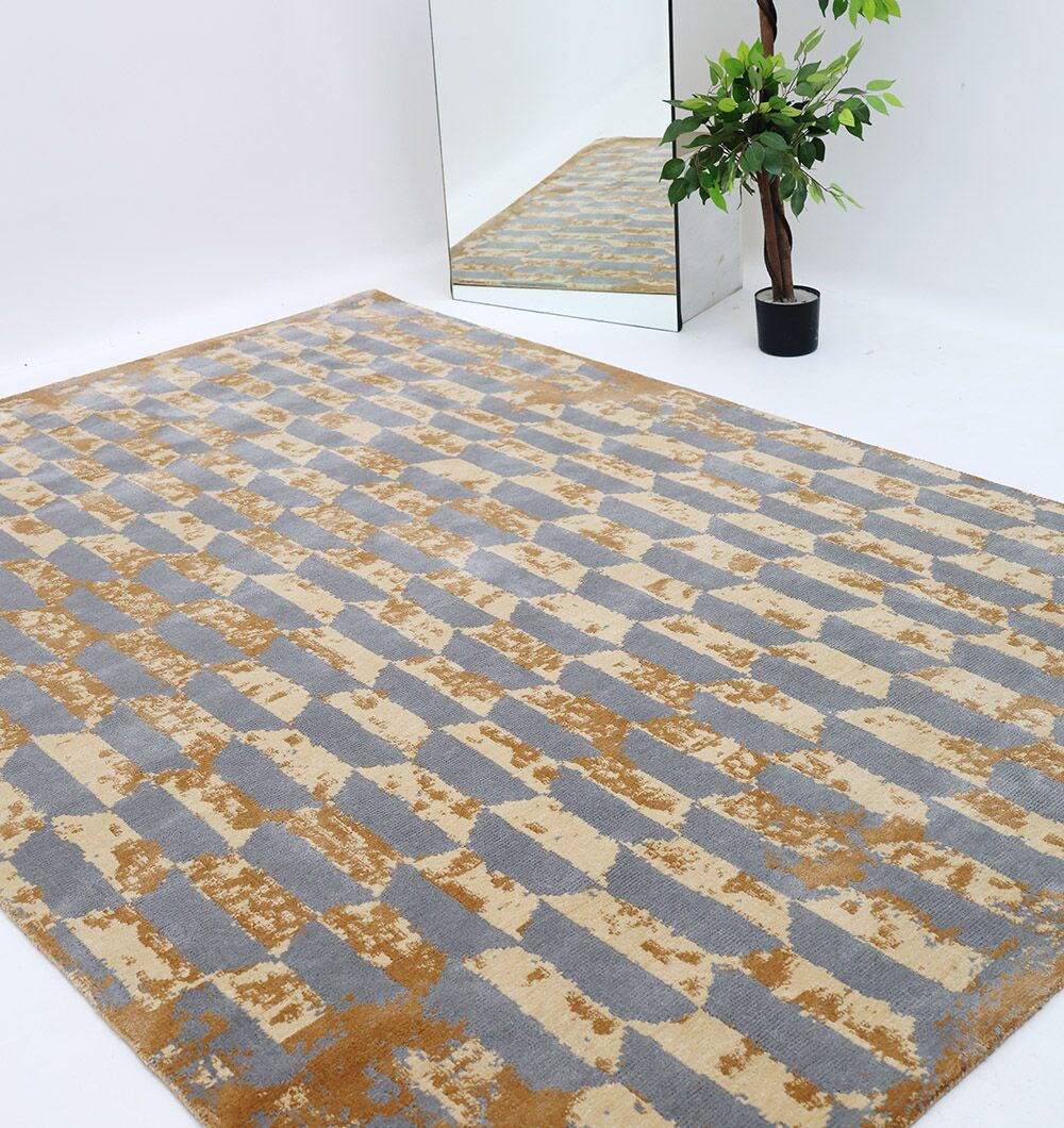 The RAMSHA HOME Home Decor Multi Color Novara Rug - CMN 82, featuring a gray and mustard geometric pattern, is placed beside a potted plant and large mirror, all set against a plain white background.