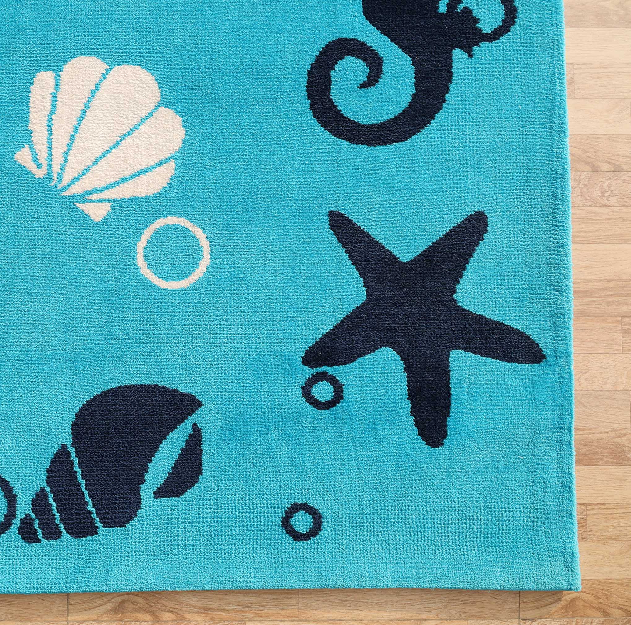 The Ultra Soft Ocean Animals Kids Rug by RAMSHA HOME (CMN 100, 200x300 cm) features dark blue starfish, seahorse, conch shell, a white seashell, and bubbles on a blue ocean theme—perfect for kids' rooms and shown here on a light wood floor.