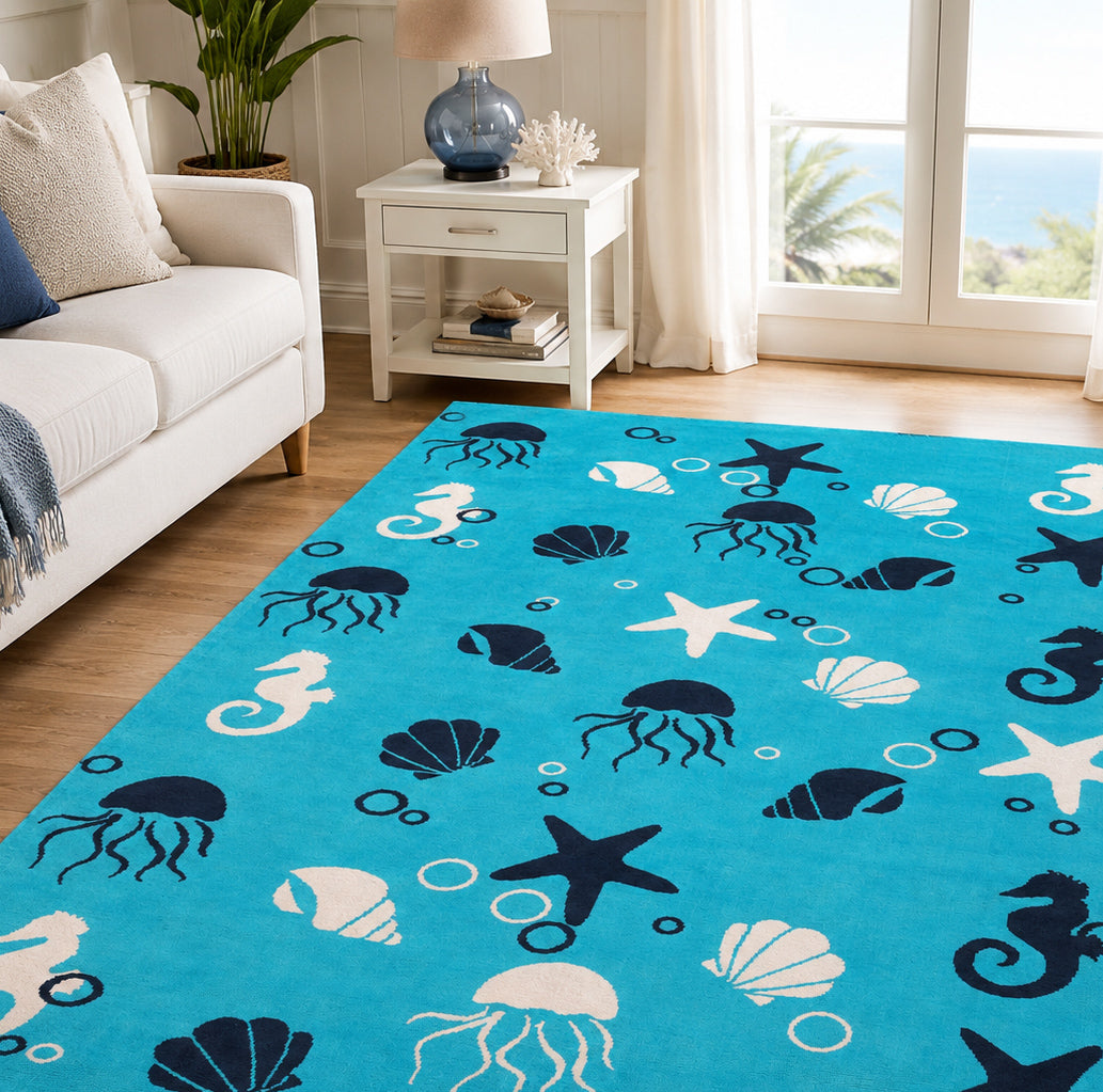 The RAMSHA HOME Ultra Soft Ocean Animals Kids Rug (CMN 100, 200x300 cm) in bright blue, with white and navy sea creatures, adds a cozy touch to a living room featuring light furniture and large windows with views of greenery.