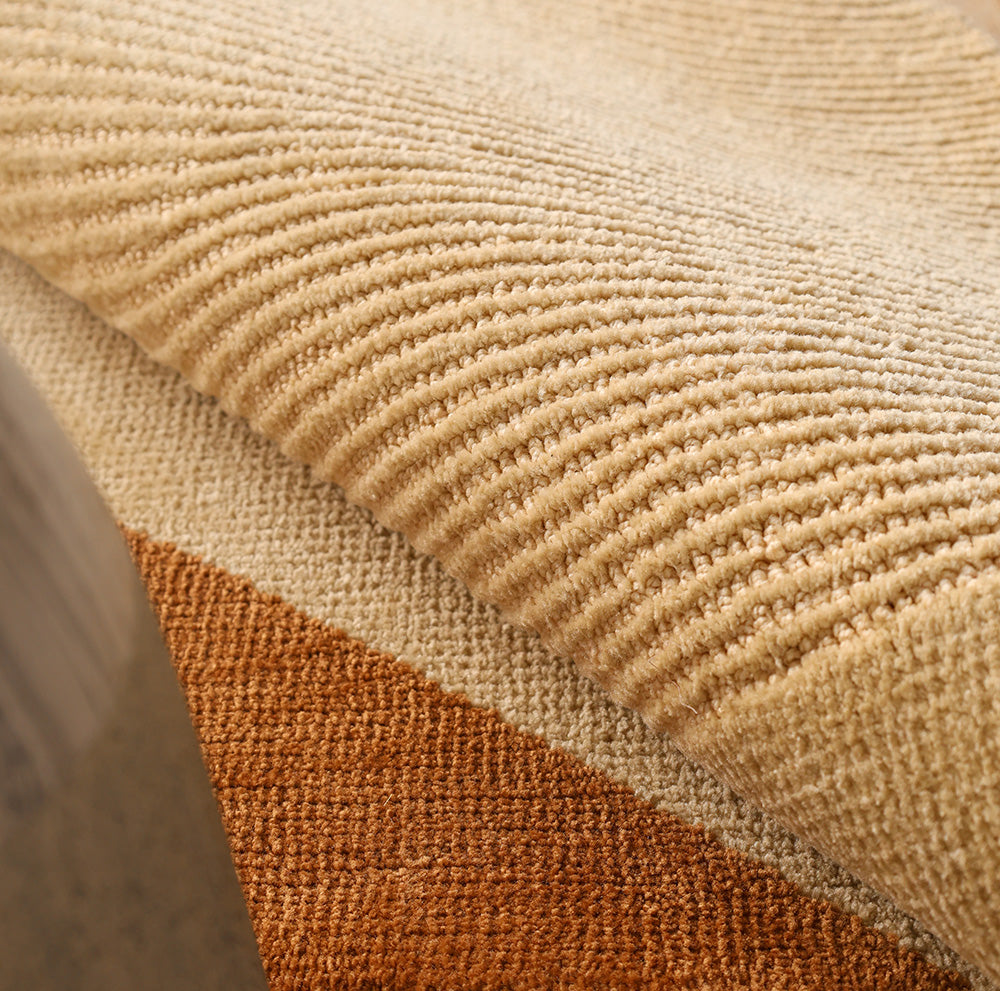 Close-up of RAMSHA HOME's Dune Flow Abstract Shaped Rug (CMN 102) in beige and terracotta, featuring textured, corduroy-like ridges and a soft surface—contemporary design inspired by desert landscapes.