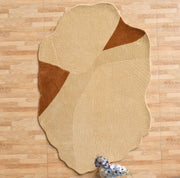 The RAMSHA HOME Dune Flow Abstract Shaped Rug in beige and terracotta (CMN 102) with textured patterns lies on a light wood floor, accented by a small bunch of white and purple flowers at the bottom edge.