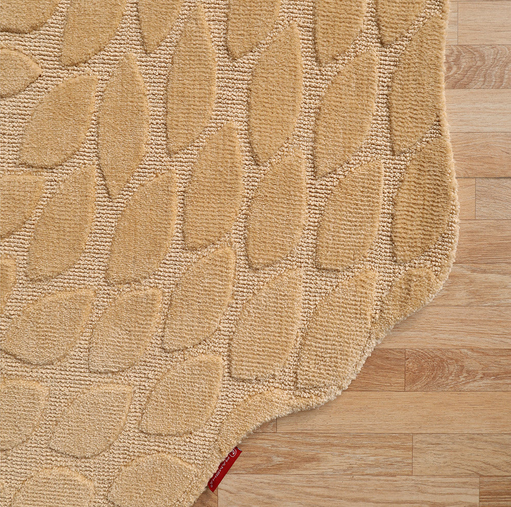 The RAMSHA HOME Autumn Leaf Organic Shaped Rug Beige CMN 103, featuring a textured raised leaf pattern and irregular edge, rests on a light wooden floor with a small red tag visible at the bottom.