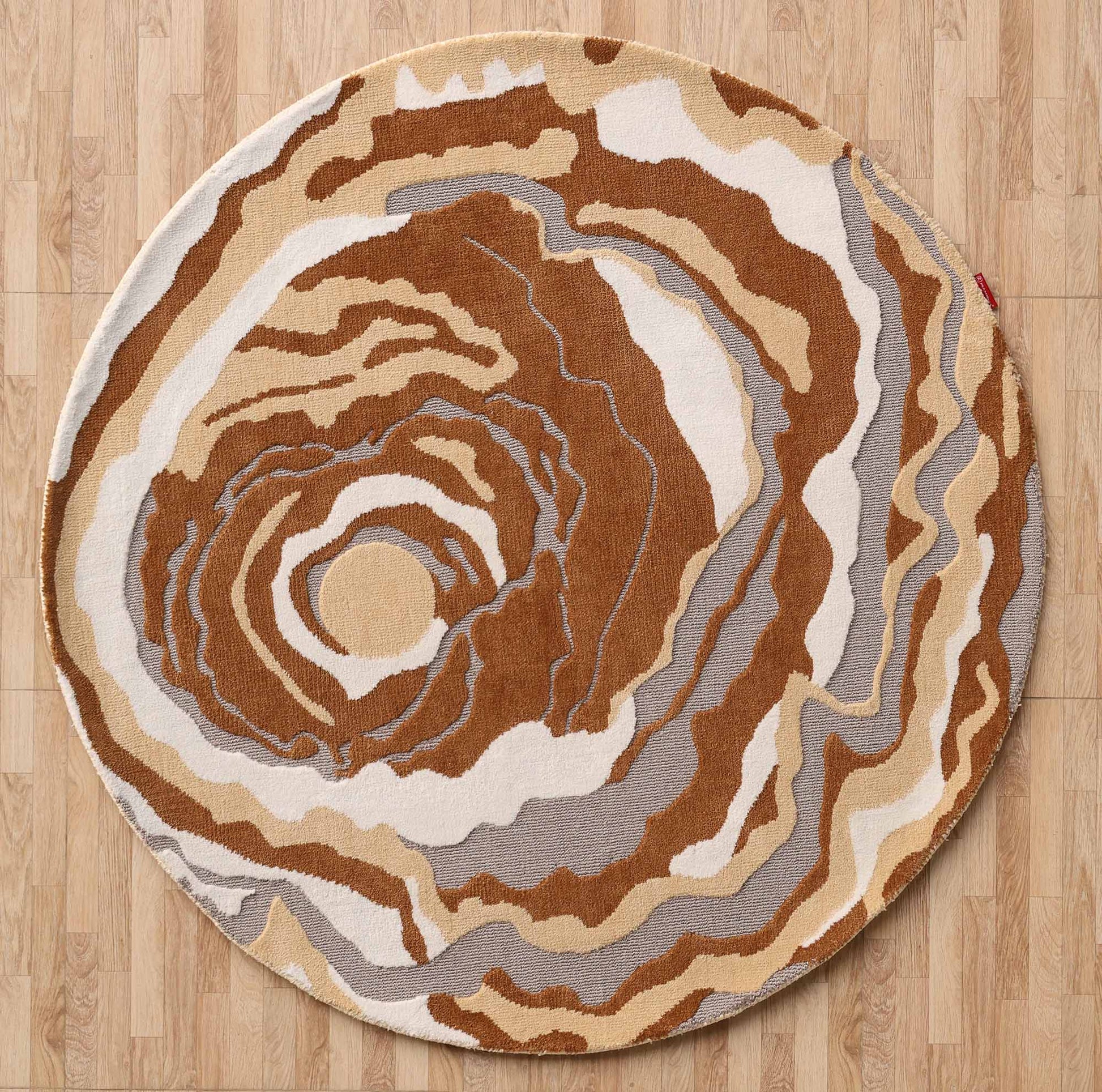 The RAMSHA HOME Modern Round Abstract Rug CMN 104 features swirling patterns in brown, beige, white, and gray, evoking wood grain or geode. It adds a modern touch and sits elegantly on a light wood floor.