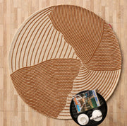 The Layered Wave Modern Round Abstract Rug CMN 106 by RAMSHA HOME features beige and brown textured wavy lines on wood flooring, with a black tray holding white cups and magazines, enhancing the contemporary look.