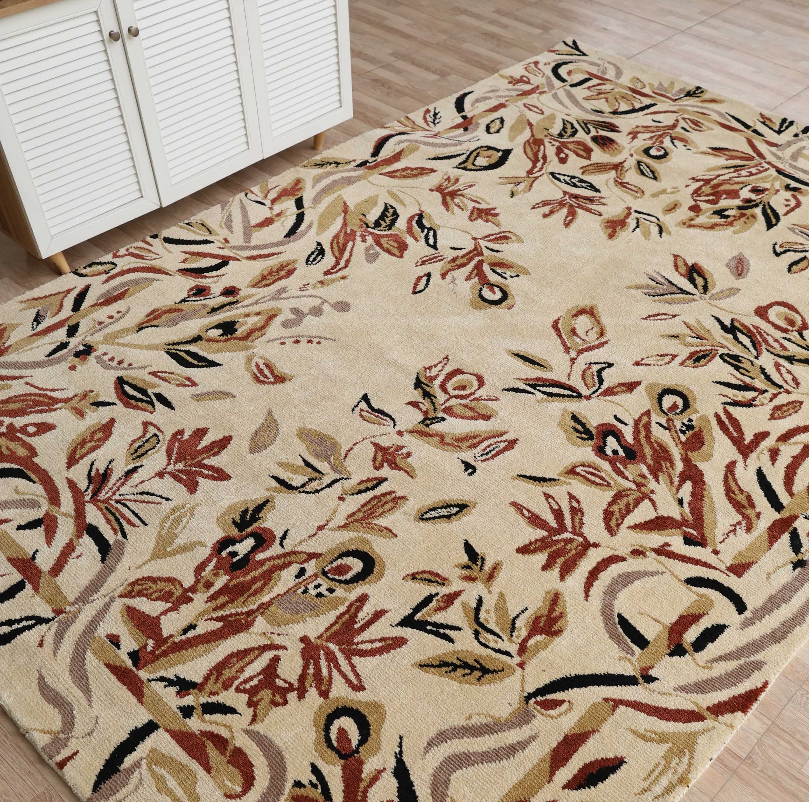 The RAMSHA HOME Vintage Floral Elegance Handmade Rug 200x300 CM -CMN 111, with its abstract botanical pattern in red, brown, green, and yellow on beige, is displayed on a light wood floor next to a white louvered cabinet.