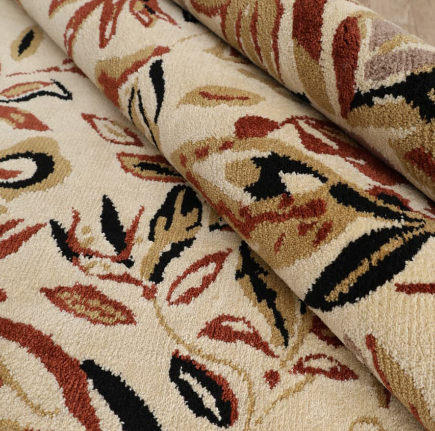 Close-up of the RAMSHA HOME Vintage Floral Elegance Handmade Rug 200x300 CM - CMN 111, featuring a textured beige surface with abstract red, black, and tan leaf patterns and an intricate design.