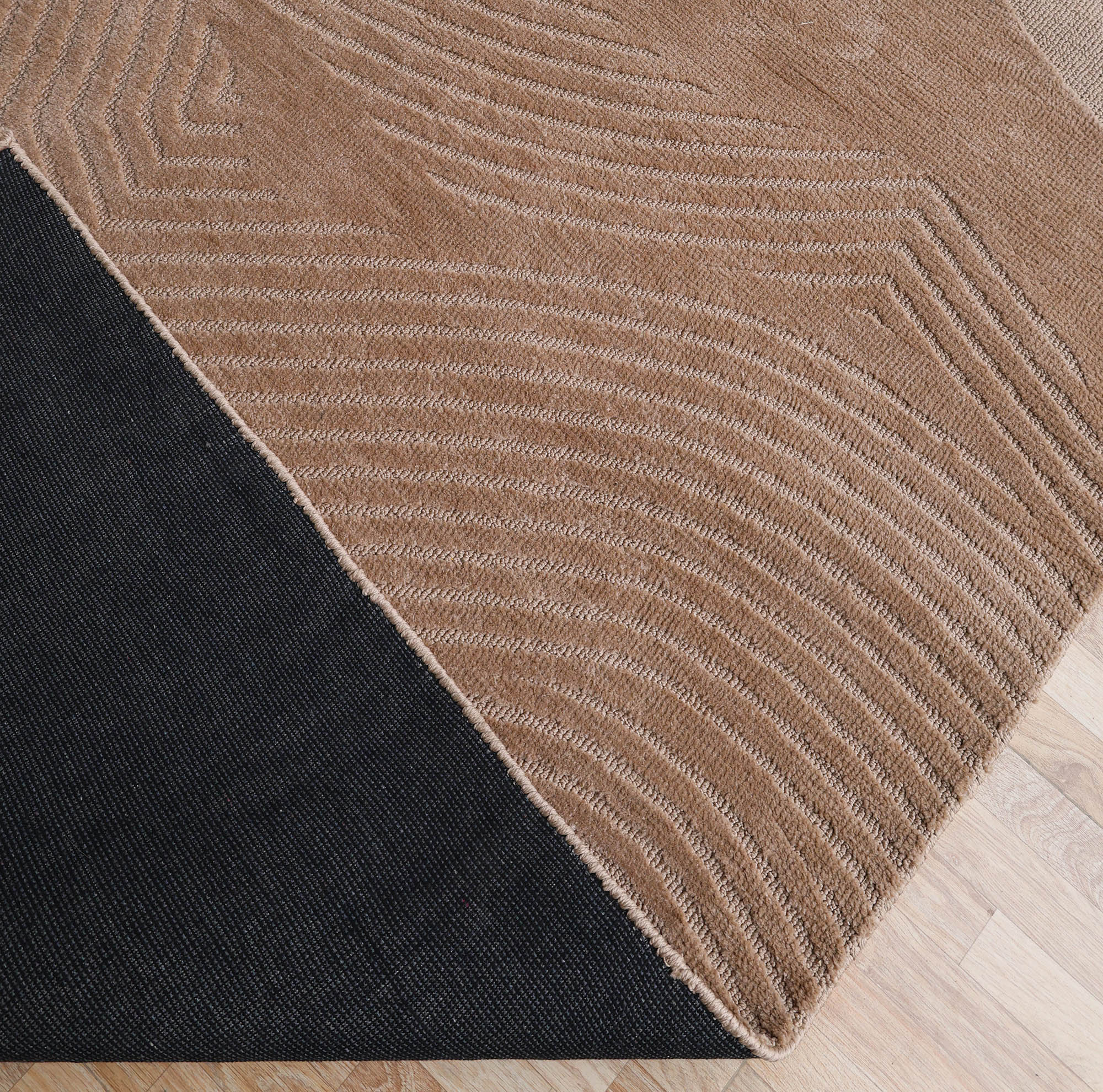 The RAMSHA HOME Terrain Design 200x300 CM Rectangle Shaped Rug CMN 112 features a modern pattern with a black triangle corner and tan wavy textured sections, shown on a light wood floor.