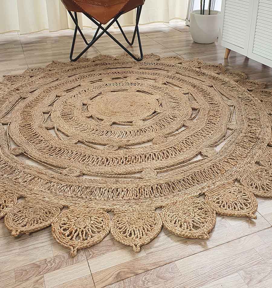 The RAMSHA HOME Natural Crochet Jute Round Rug - CR 013 features intricate braiding, decorative patterns, and a scalloped edge, perfect for adding style to modern rooms with wooden floors, leather chairs, and white furniture.