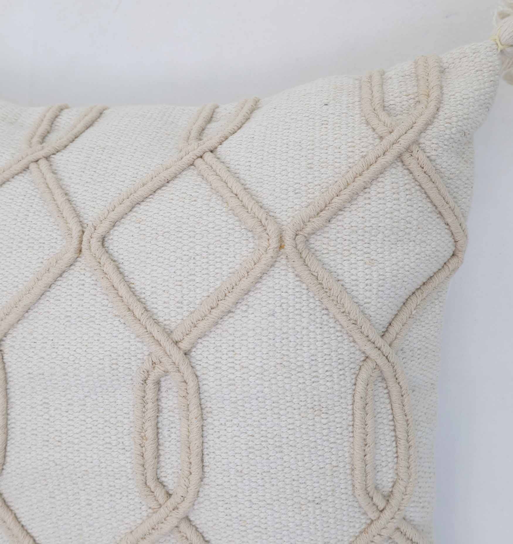 Close-up of the Home Decor Tassel Cushion (Natural & White, 45x45cm) by Ramsha Home. Featuring raised geometric rope patterns, only the top corner of this stylish cushion is visible against a plain white background.