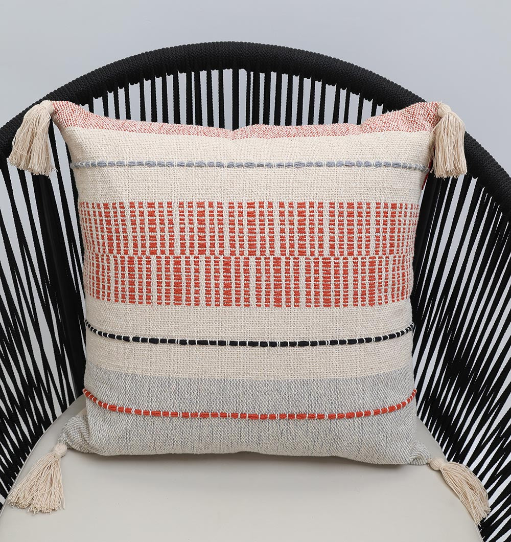 The Multi Color Home Decor Cushion - CS 314 B by Ramsha Home features red, black, and gray textured stripes on beige cotton with tasseled corners. Stylish for sofas or chairs, this luxury cushion adds a vibrant touch to your home decor.