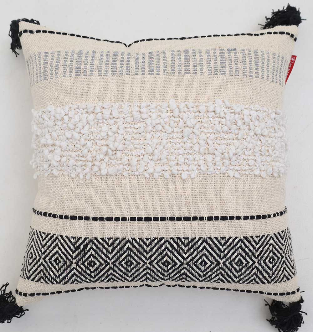 The Multi Color Home Decor Cushion - CS 314 C by Ramsha Home features a color-blocked cotton design with textured cream and white center, bold black geometric patterns, and decorative tassels on each corner. Shown on a plain white background.