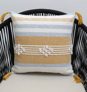 The Multi Color Home Decor Cushion - CS 315 A by Ramsha Home features white, blue, and mustard yellow stripes with white center knots and yellow tassels on each corner, shown on a black woven chair.