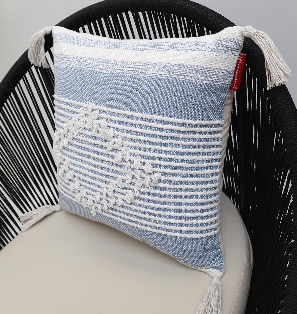 The Multi Color Home Decor Cushion - CS 315 B from Ramsha Home features blue and white cotton with corner tassels, textured patterns, color blocking, and a raised diamond design, adding elegance to any black woven chair.