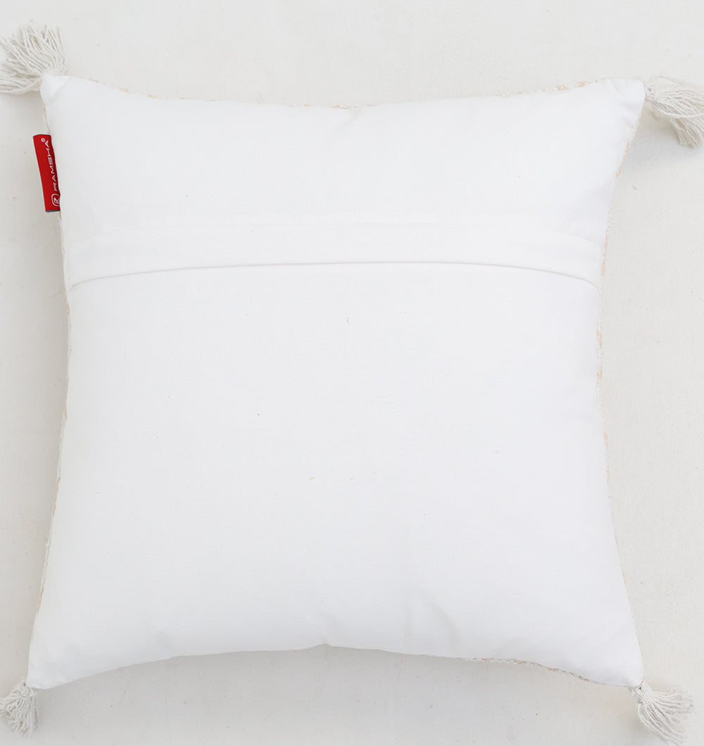 The White and Peach Color Cushion 45x45 cm CS 316 from Ramsha Home features plain fabric, tassels on two corners, and a red tag on the left side. This stylish cushion adds subtle elegance to light backgrounds.