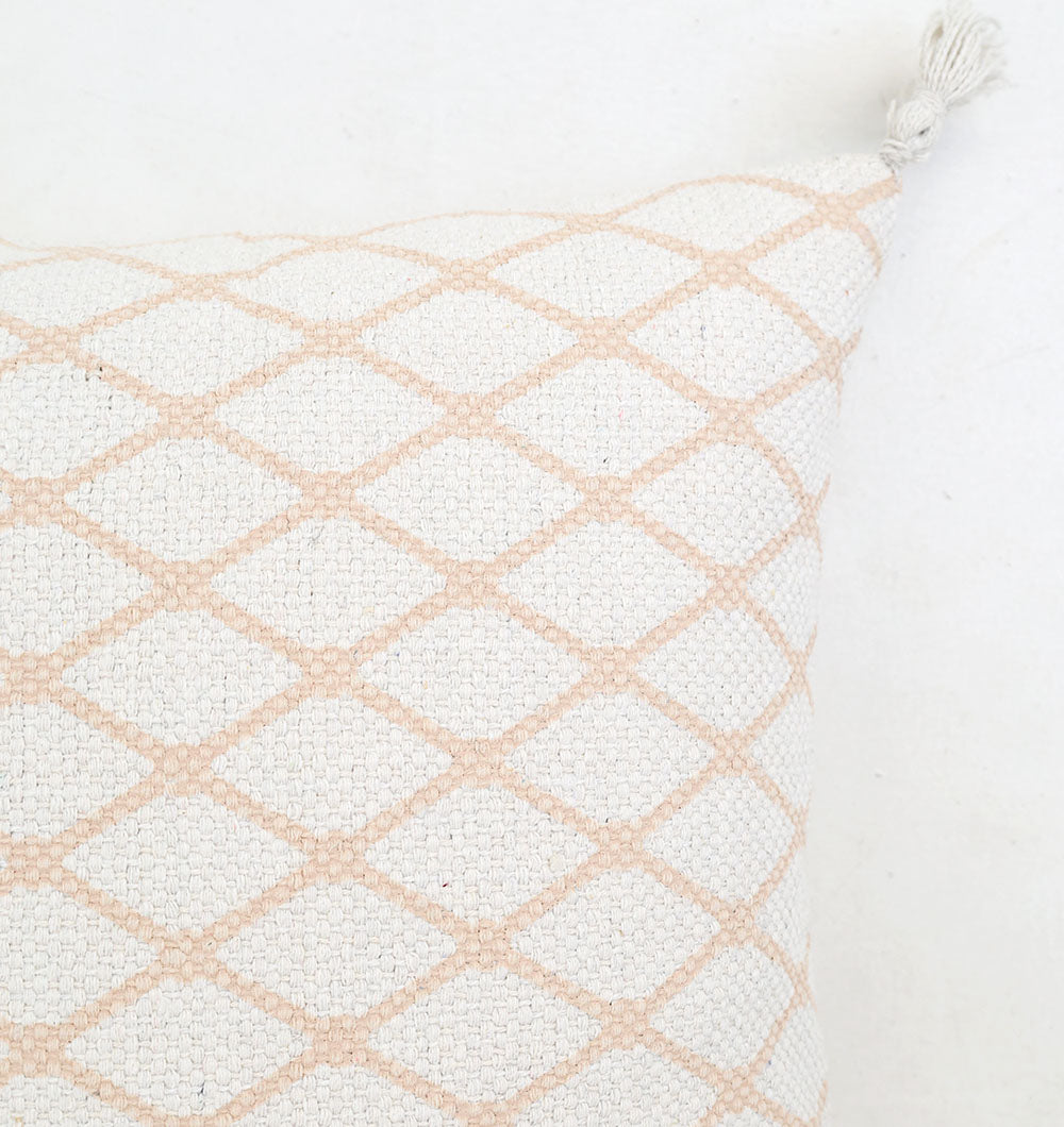 A close-up of the Ramsha Home White and Peach Color Cushion 45x45 cm CS 316, showcasing its textured white surface with a light beige diamond pattern and a corner tassel, set against a white background.
