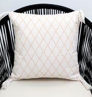 The White and Peach Color Cushion 45x45 cm CS 316 by Ramsha Home, a luxury rugs & home furnishings brand in the UAE, features a light beige diamond pattern with tasseled corners, shown here on a black woven chair with curved slats.