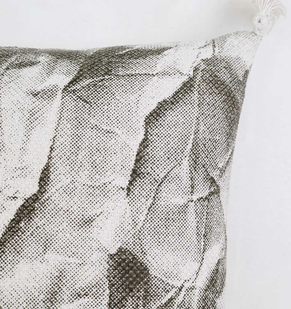 Close-up of the Ramsha Home White and Grey Printed Cotton Cushion 45x45 cm (CS 320), featuring a black and white crumpled paper pattern and a white tassel on the top right corner. Perfect for adding elegance to your home décor. Plain white background.