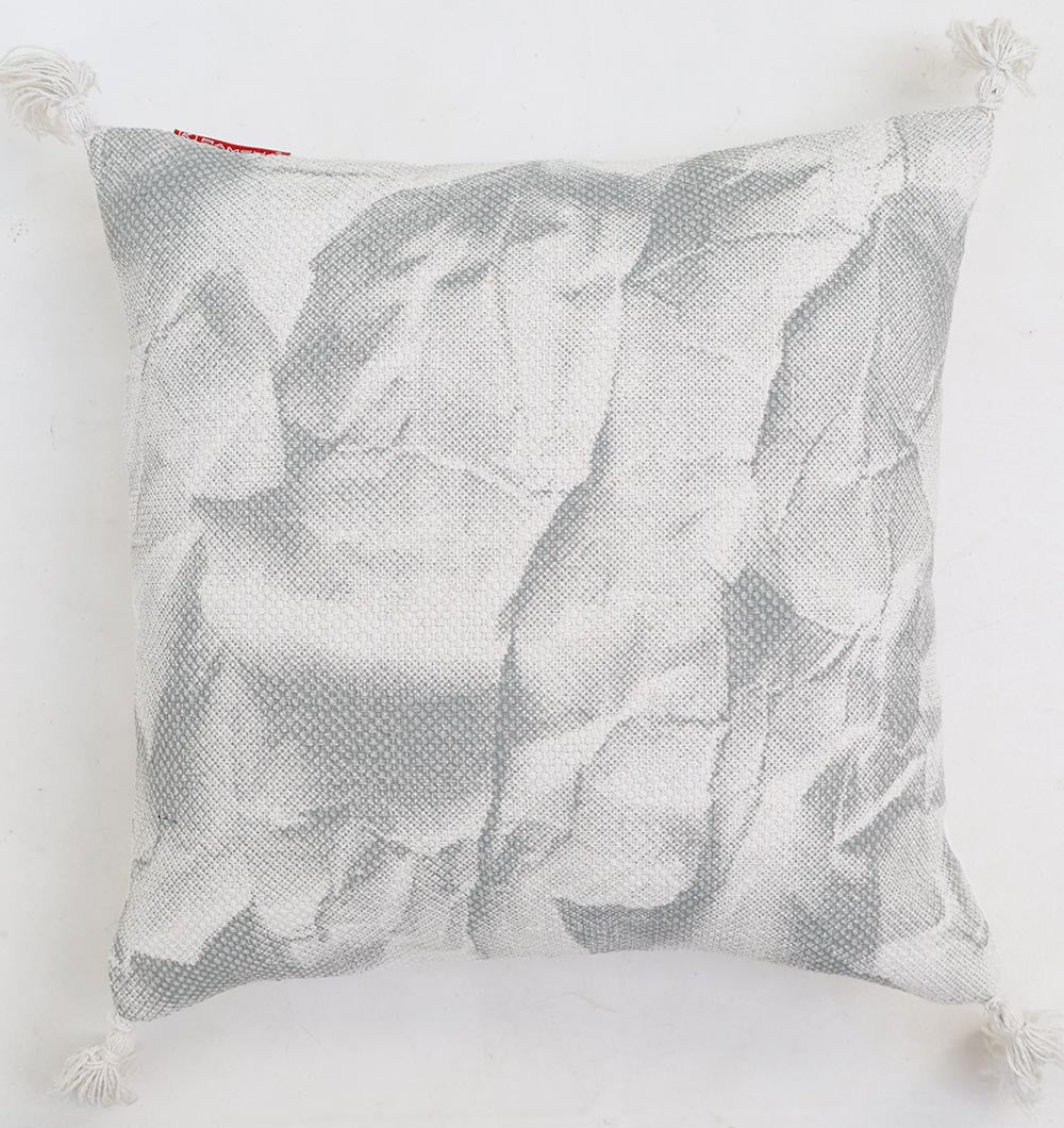 The Ramsha Home White and Grey Printed Cotton Cushion 45x45 cm (CS 321) features a textured abstract pattern with corner tassels, adding a modern touch to your space. Luxury home furnishing from the UAE displayed on a white background.