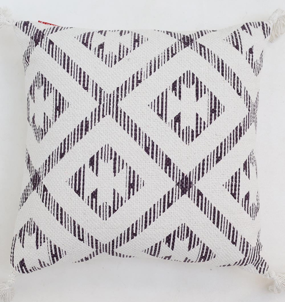 The Ramsha Home White and Grey Printed Cotton Cushion 45x45 cm (CS 322) features a white background, geometric diamond pattern in dark lines, woven texture, and decorative tassels—perfect for stylish home decor.