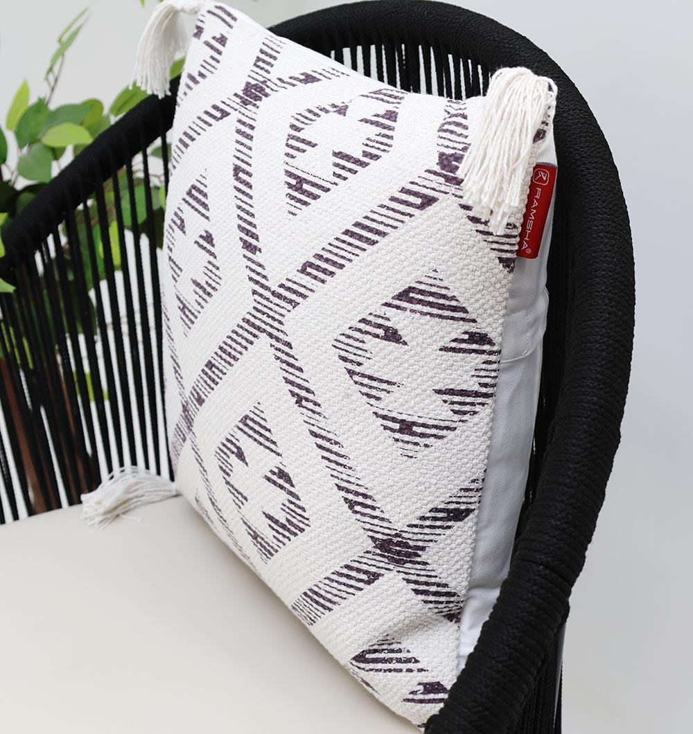 The White and Grey Printed Cotton Cushion 45x45 cm CS 322 from Ramsha Home rests on a black rope chair, with a green plant in the background.