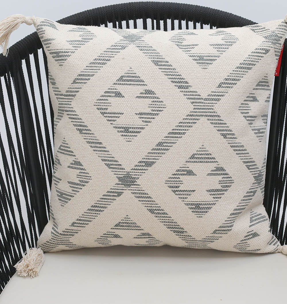 The Ramsha Home Cream and Grey Printed Cotton Cushion 45x45 cm (CS 326) features a geometric diamond and stripe pattern and a decorative tassel, perfect for adding style to your space.