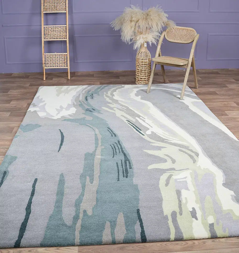 The Beautiful Hand-Tufted Rug - CWL 11 (200x300cm) by RAMSHA HOME in blue grey with abstract patterns decorates a wooden floor, paired with a woven chair, tall pampas grass basket, and wooden ladder against a purple wall.