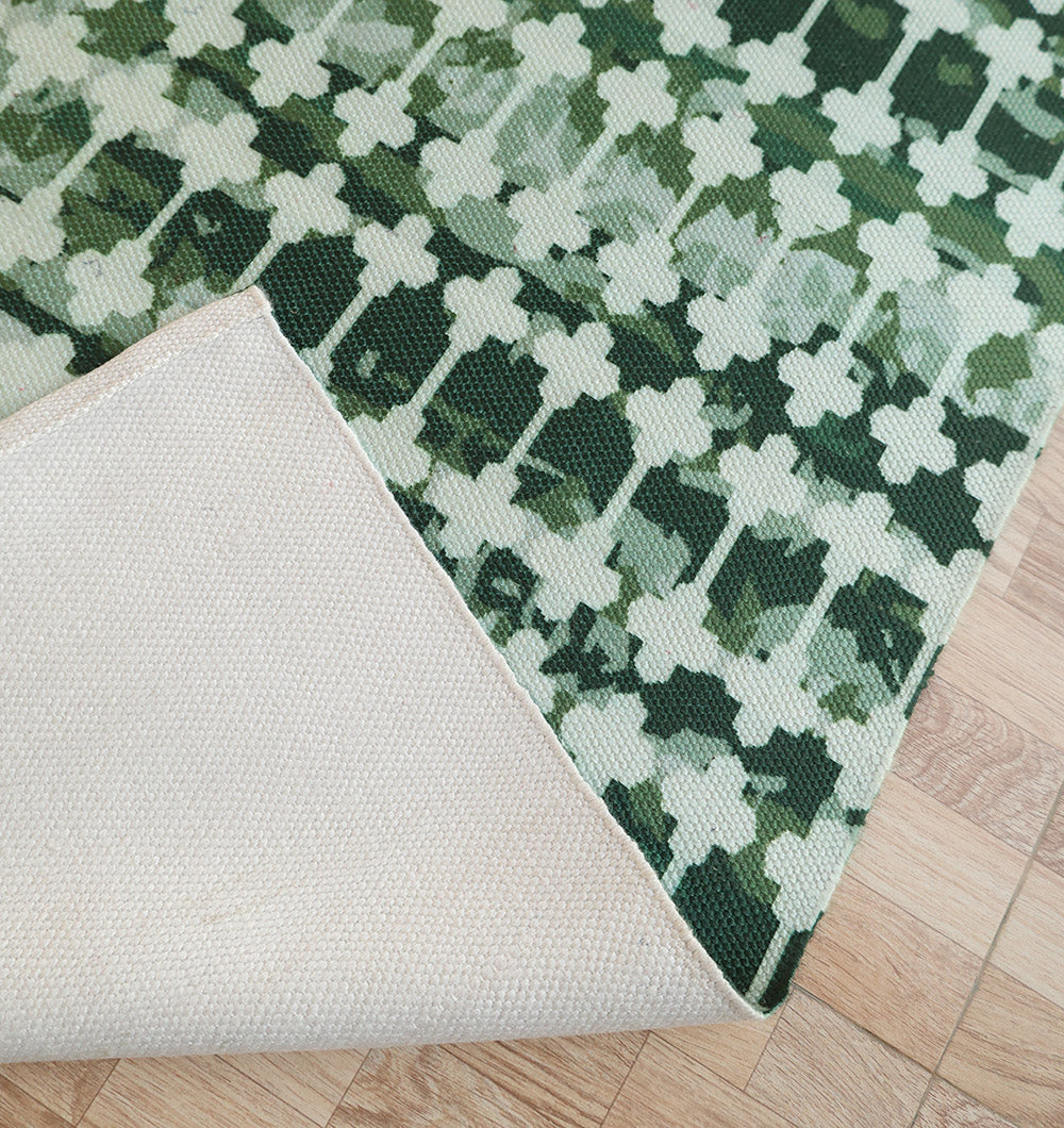 The RAMSHA HOME Emerald Mosaic Digital Printed Rug for Living Room DD-046 features a white geometric floral design on emerald green, with a plain beige underside, and is shown partially flipped over on a light wood floor.