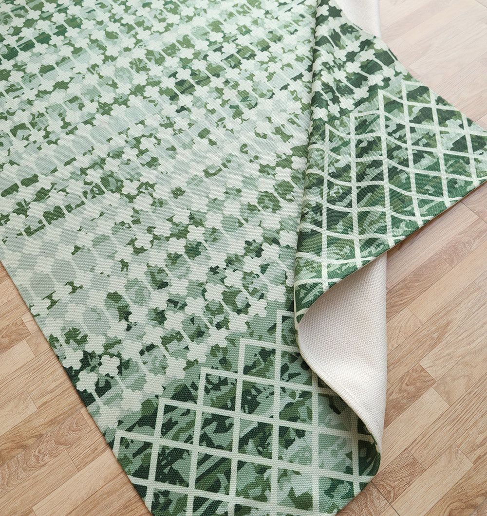 The RAMSHA HOME Emerald Mosaic Digital Printed Rug for Living Room DD-046, in emerald green with a bold white pattern, is partially folded to display its geometric design underside, adding modern elegance to a light wood floor.