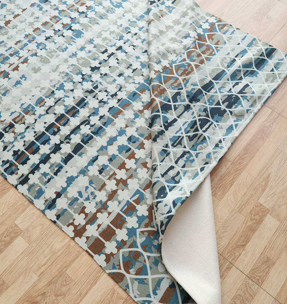 The RAMSHA HOME Modern Mosaic Digital Printed Rug for Living Room DD-047 features geometric patterns in blue, brown, and beige, shown partially flipped on a light wood floor to reveal its contrasting modern underside design.