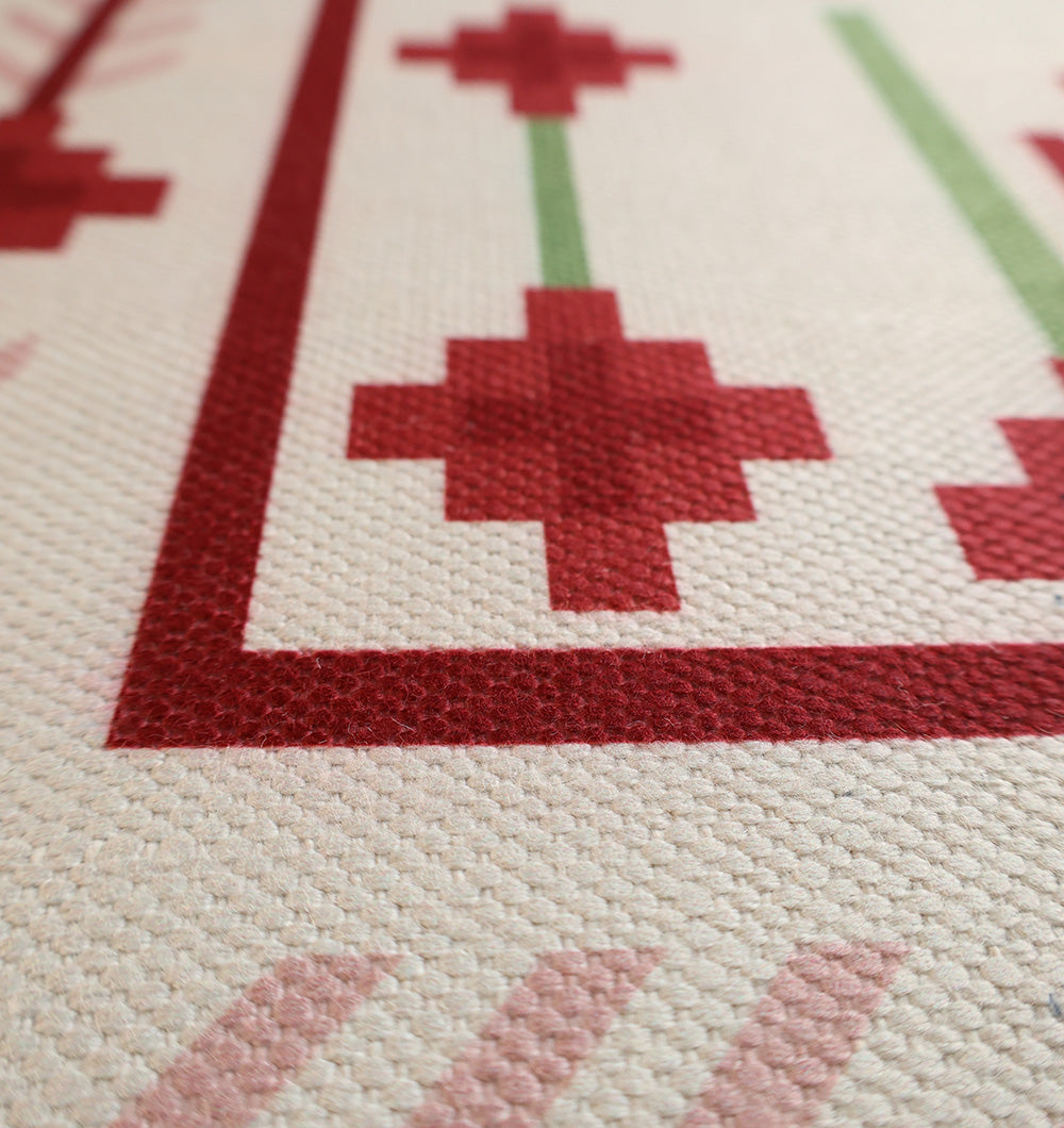 Close-up of the RAMSHA HOME Traditional Red Floral Digital Printed Rug – Bohemian Area Rug DD-048, showing a textured geometric pattern with red, pink, and green shapes on a cream background, bordered with cross-like motifs.