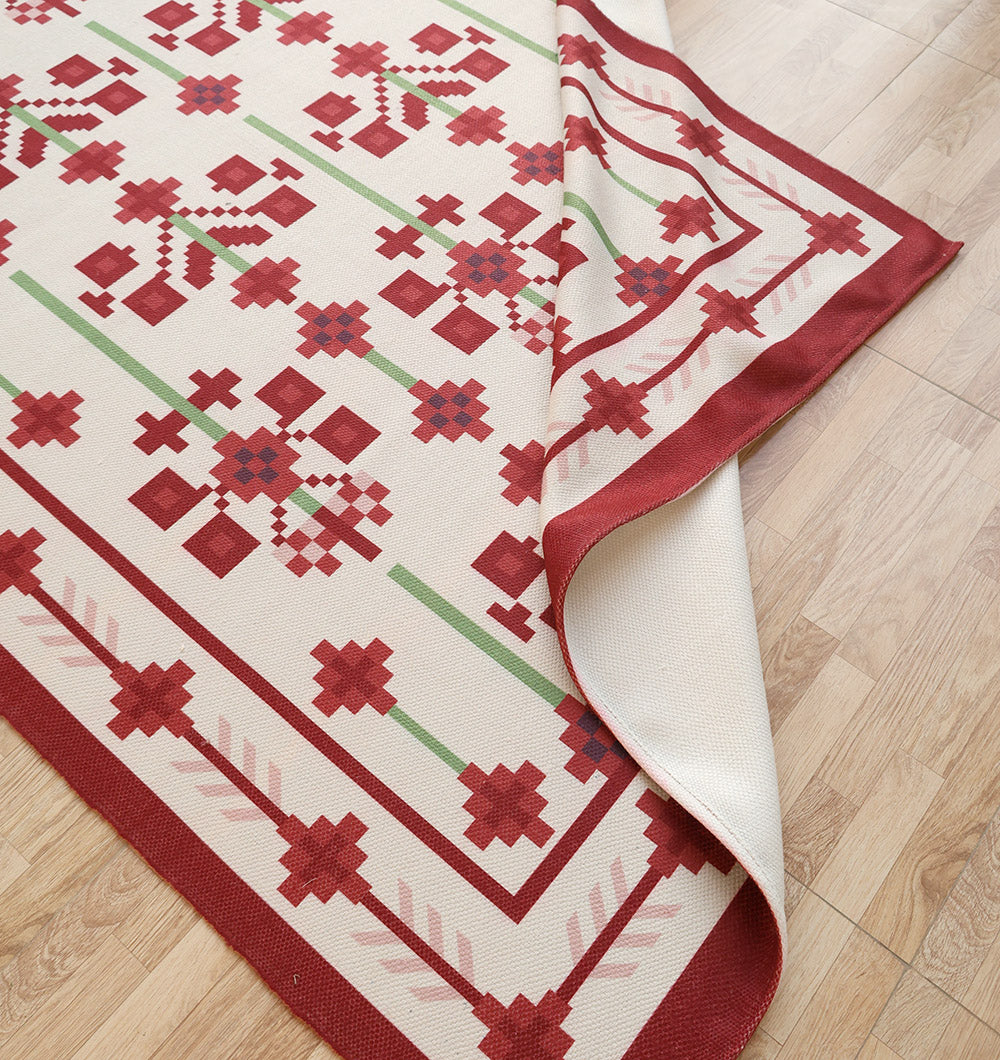 The RAMSHA HOME Traditional Red Floral Digital Printed Rug – Bohemian Area Rug DD-048 features red floral patterns and is shown partially folded on a light wood floor, displaying its plain underside.