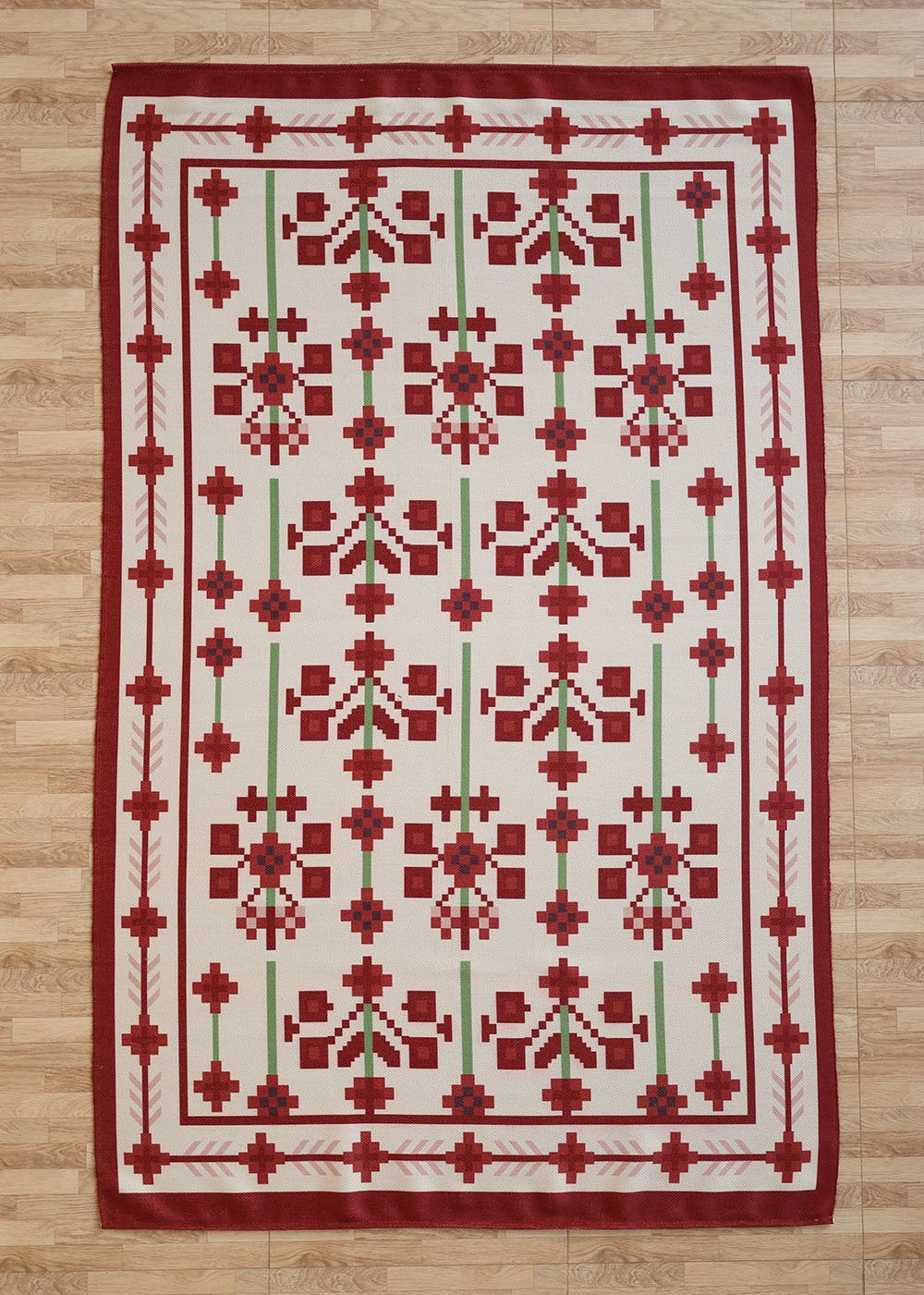 The RAMSHA HOME Traditional Red Floral Digital Printed Rug – Bohemian Area Rug DD-048 features a symmetrical geometric and floral pattern in red, green, and white, and is shown on a light wood floor.