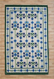 The RAMSHA HOME Blue Traditional Floral Digital Printed Rug – Bohemian Area Rug DD-049 features a geometric floral blue and green pattern with a blue and green border, displayed on a light wood floor.