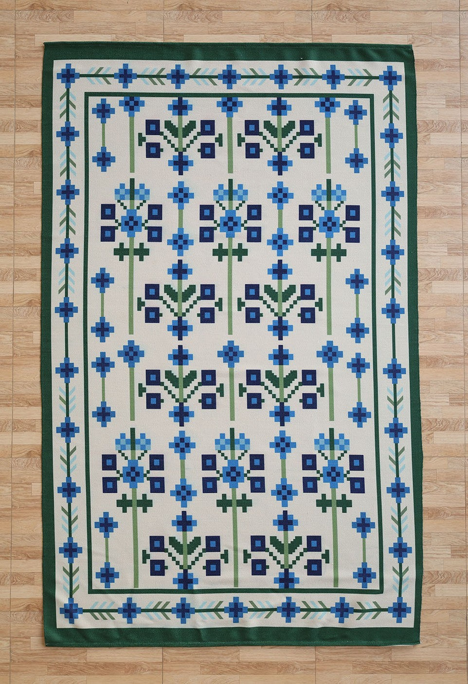 The RAMSHA HOME Blue Traditional Floral Digital Printed Rug – Bohemian Area Rug DD-049 features a geometric floral blue and green pattern with a blue and green border, displayed on a light wood floor.